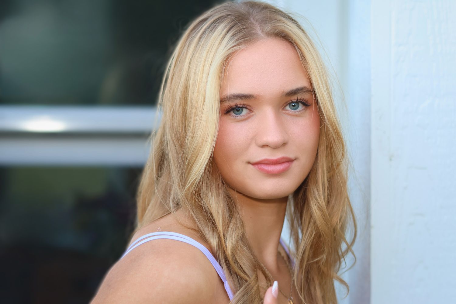 High school senior girl looking at camera with a natural face, large eyes and wavy blond hair.
