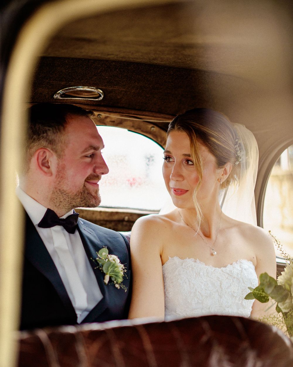 Romantic moment captured inside vintage car on wedding day.