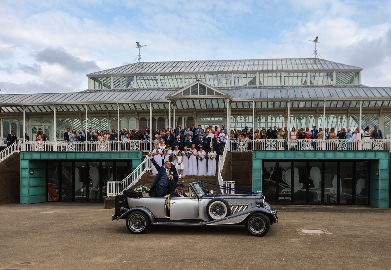 Vintage cars lined up outside a historic pavilion building with classic architecture.