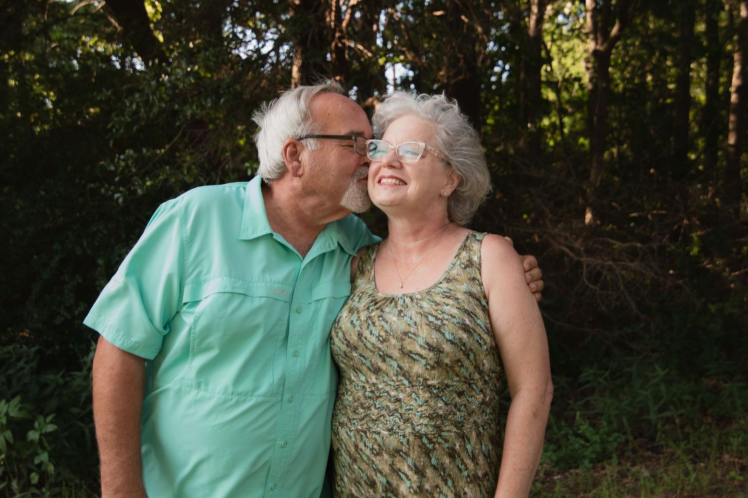 Senior couple sharing a tender moment outdoors in summer clothing.
