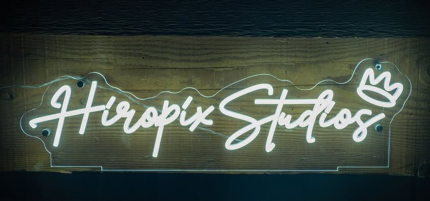 Illuminated neon sign reading Hirepix Studios with crown design.
