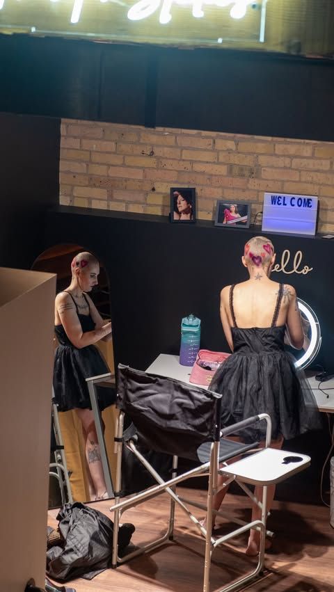 Professional photography setup in a studio with makeup chairs and welcome sign on brick wall.