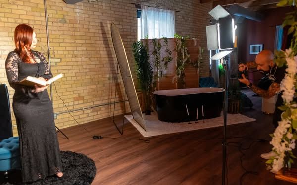 Photography studio setup with wooden floors and decorative plants against a brick wall.