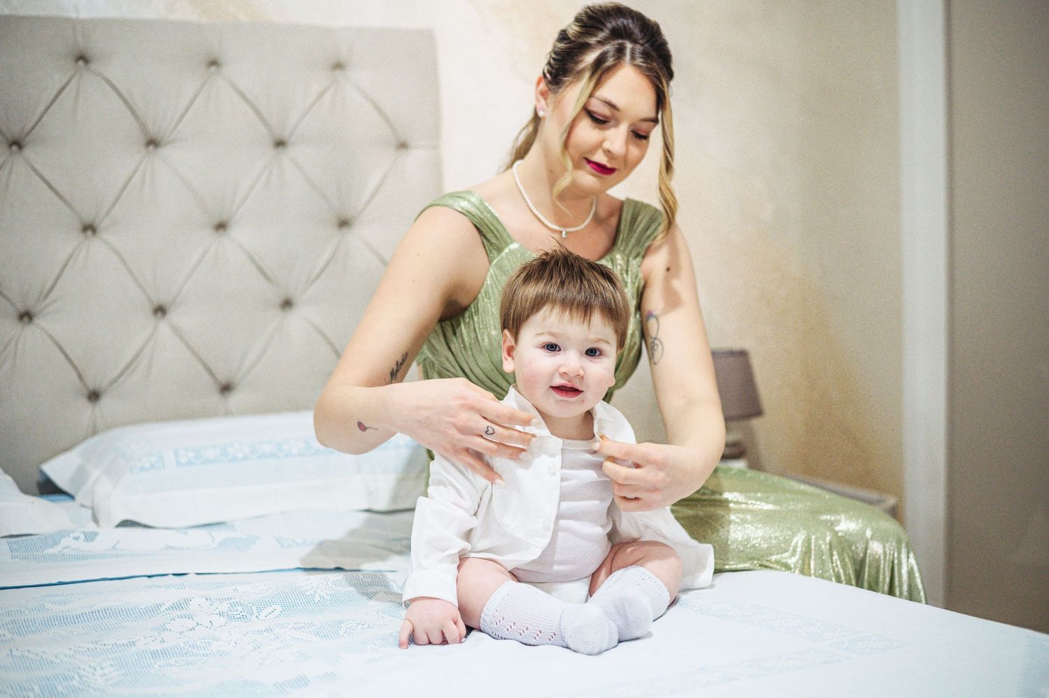 Playful interaction between caregiver and baby on blue bedding.