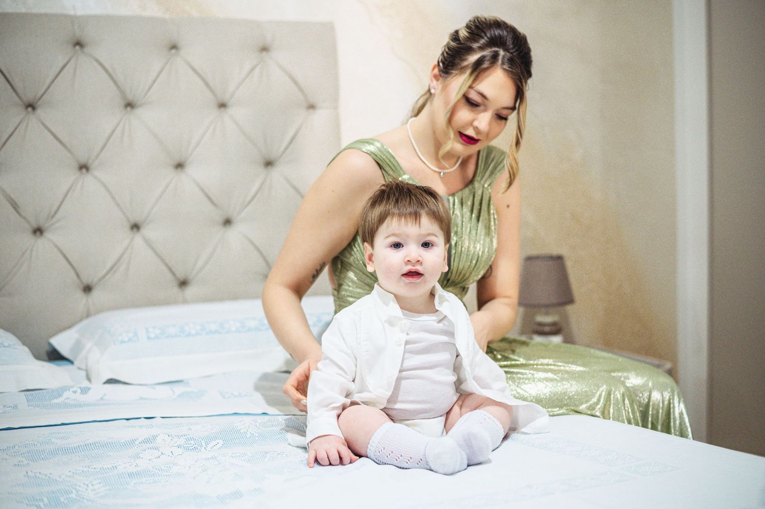 Sweet moment between caregiver and baby on bed with tufted headboard.
