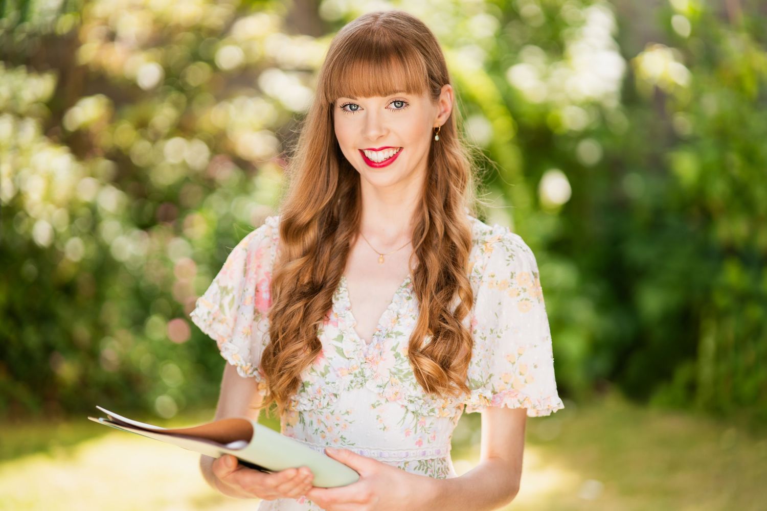A vintage-styled portrait of someone holding a book in a garden setting. Wedding celebrant photography.