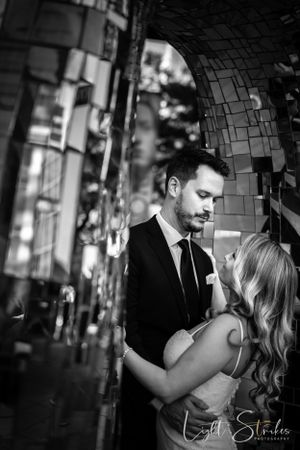 Artistic black and white romantic wedding photo showing a tender intimate moment under an archway with mosaic tiles.