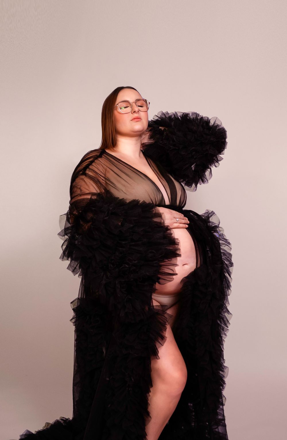 Séance photo artistique en studio d'une femme enceinte, capturée dans un style épuré et élégant, mettant en valeur la beauté de la grossesse