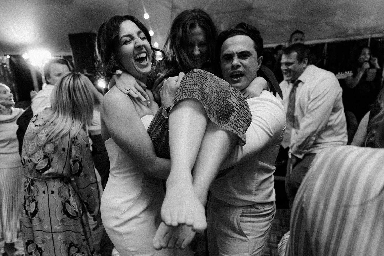 Wedding guests dance and laugh together during a lively reception celebration in black and white on Fox Harb'r Resort wedding venue