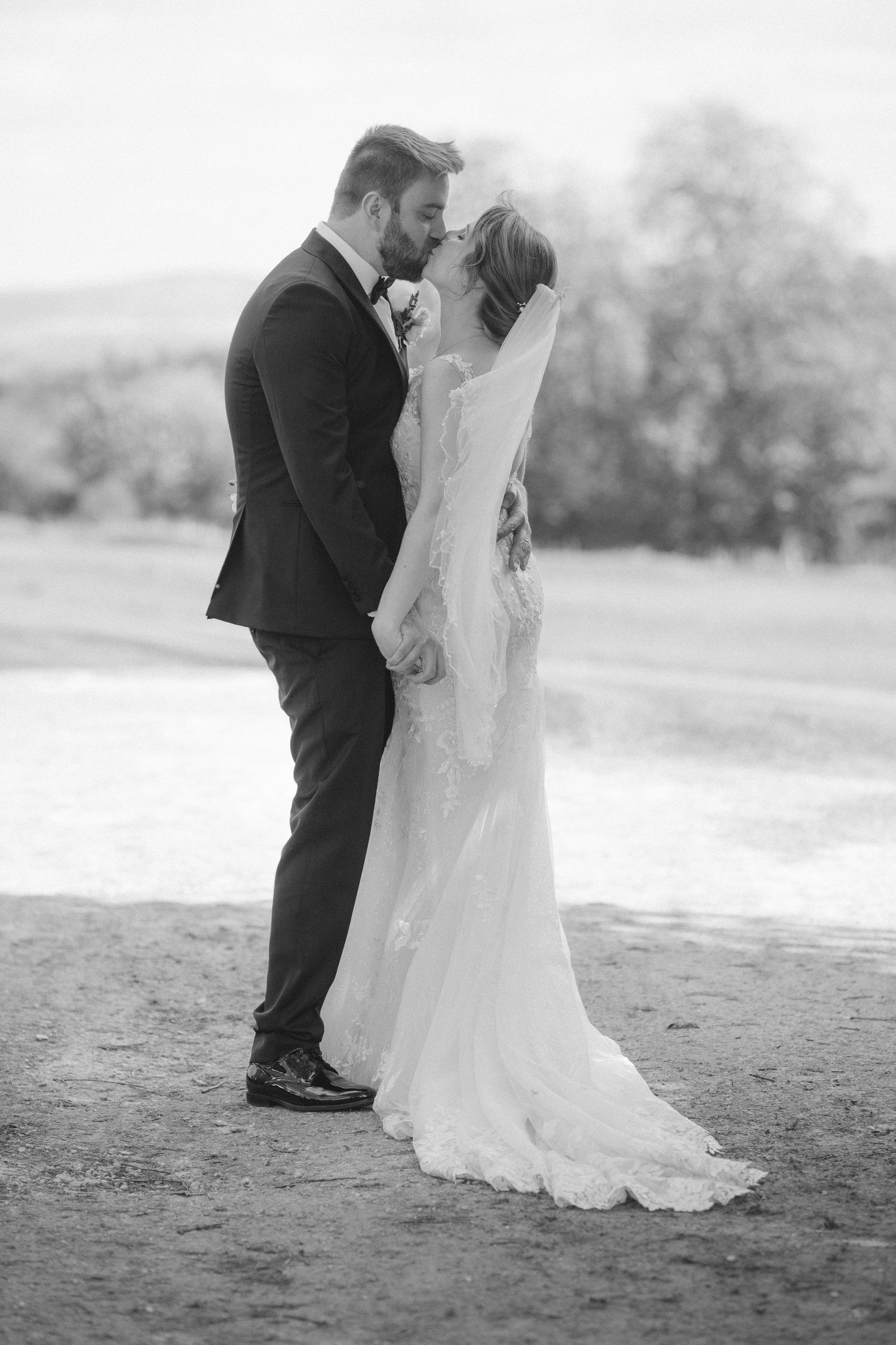 Romantic black and white wedding photo of couple standing close together at Fox Harb'r Resort golf course with flowing white dress and veil.
