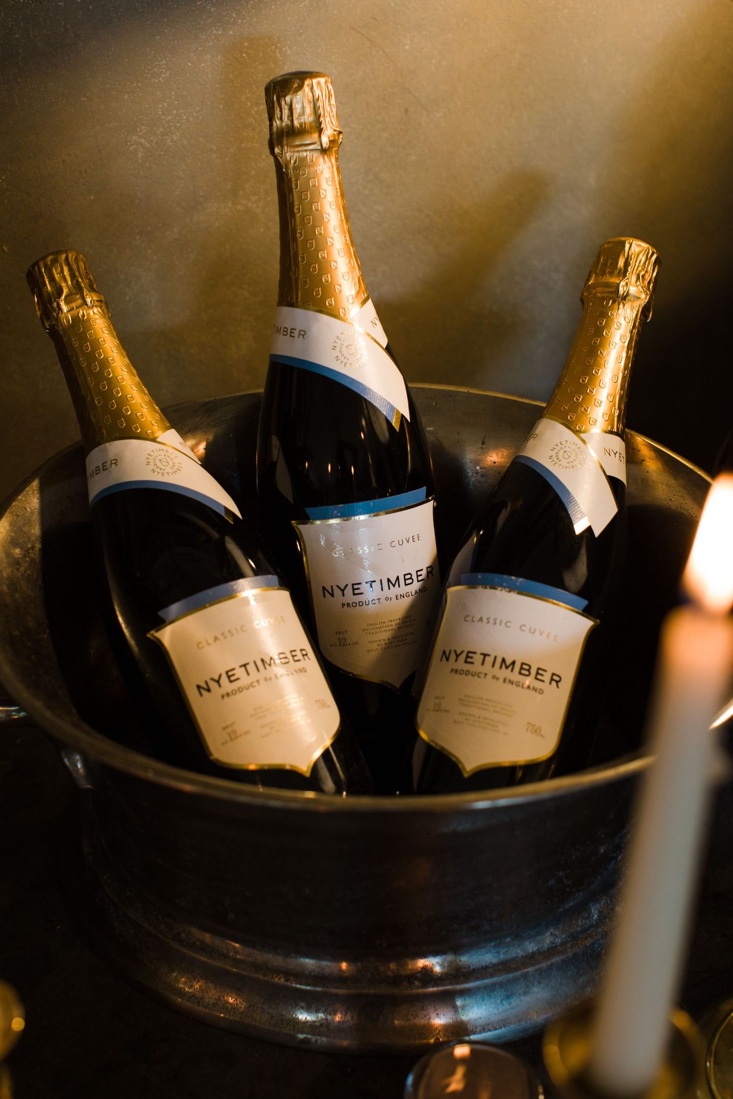 Three champagne bottles of Nye Timber wine chilling in an ice bucket with moody lighting at Nova Scotia wedding venue Fox Harb'r Resort