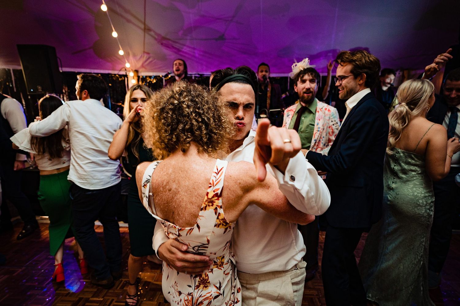 Groom dancing with mother at a lively wedding reception with purple mood lighting in the background at Fox Harb'r Resort, Nova Scotia