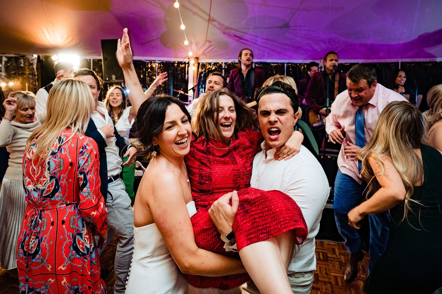 Wedding guests dance and celebrate enthusiastically under a white tent during an outdoor reception celebration at Nova Scotia wedding venue