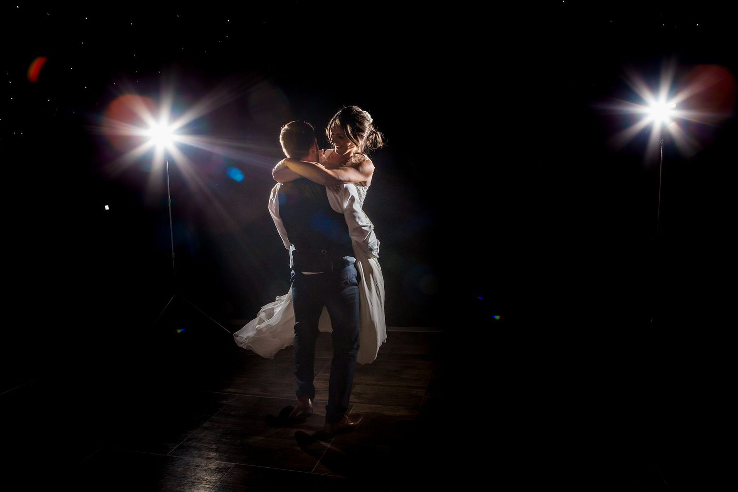 A couple shares an intimate dance moment under dramatic spotlights on a dark dance floor at Fox Harb'r Resort wedding venue, Nova Scotia