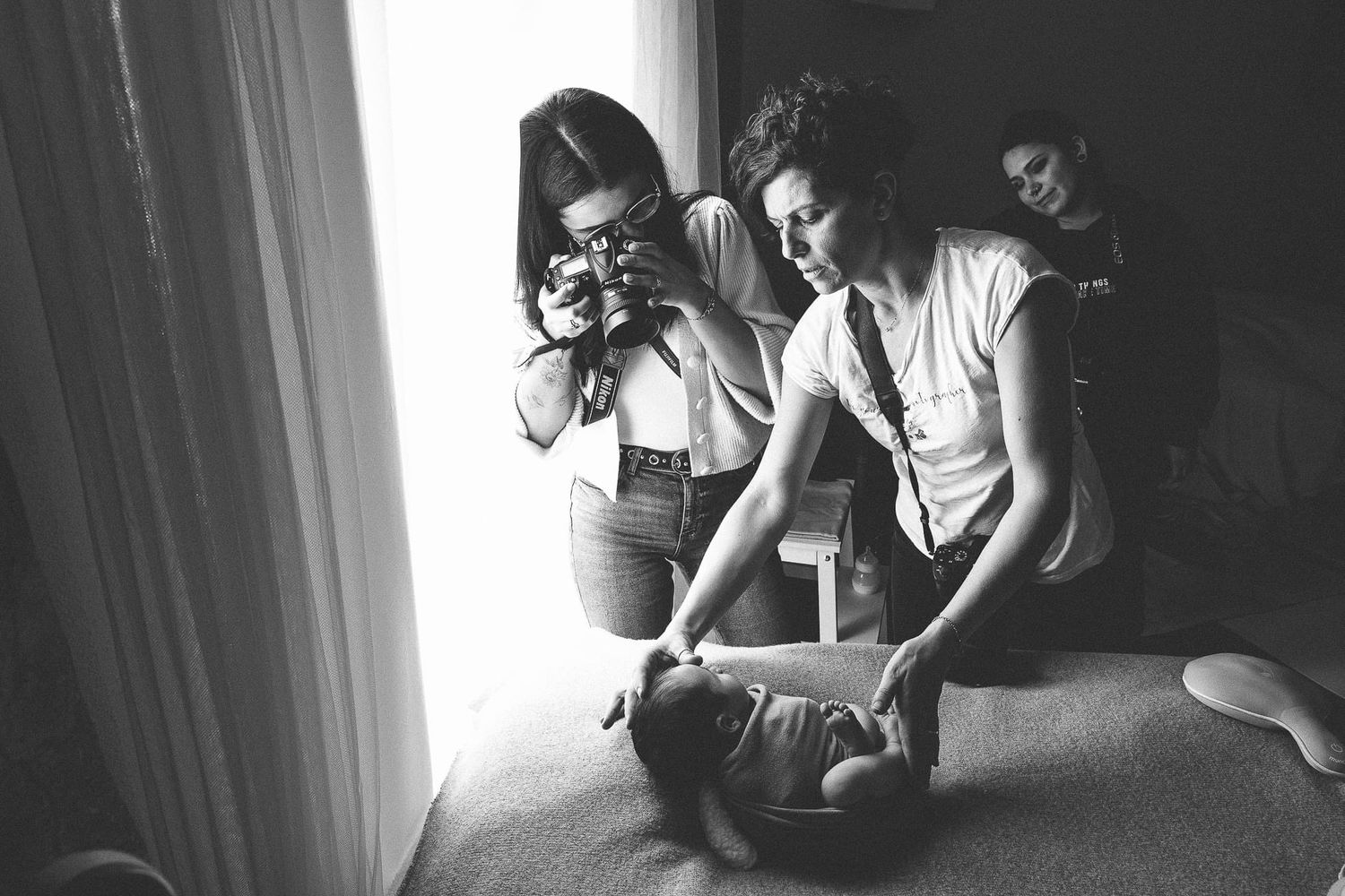 Gabriella Fotografie che cattura foto di neonati in un ambiente di luce naturale vicino a una finestra durante un workshop.
