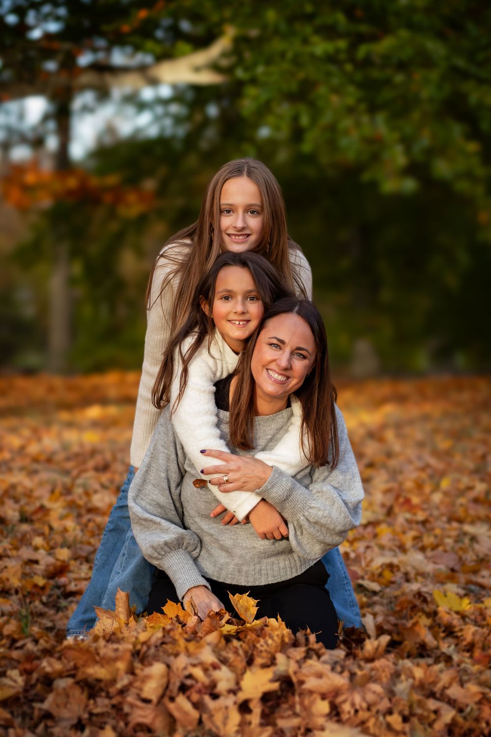 familjefoto mamma två barn döttrar systrar i höstlöv familjeporträtt Tyresö Stockholm. Fotograf Tyresö slott. Vacker miljö utomhus.