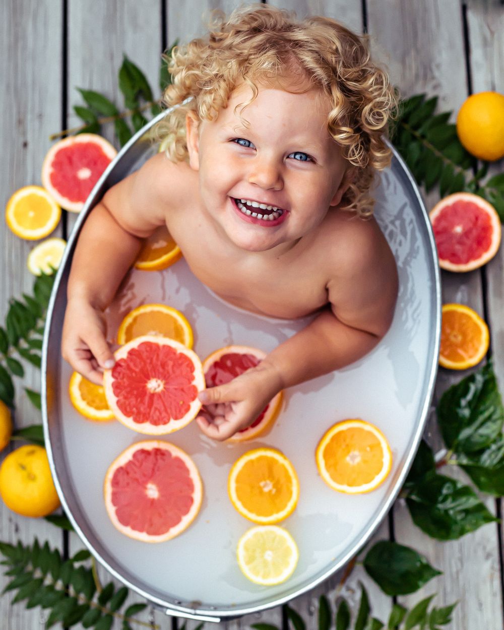 Mjölkbad, fotogragfering, Barnfoto, bebis i mjölkbad, blommor, blad, citrusfrukt. Badbalja, foto. Fotograf tyresö, stockholm.