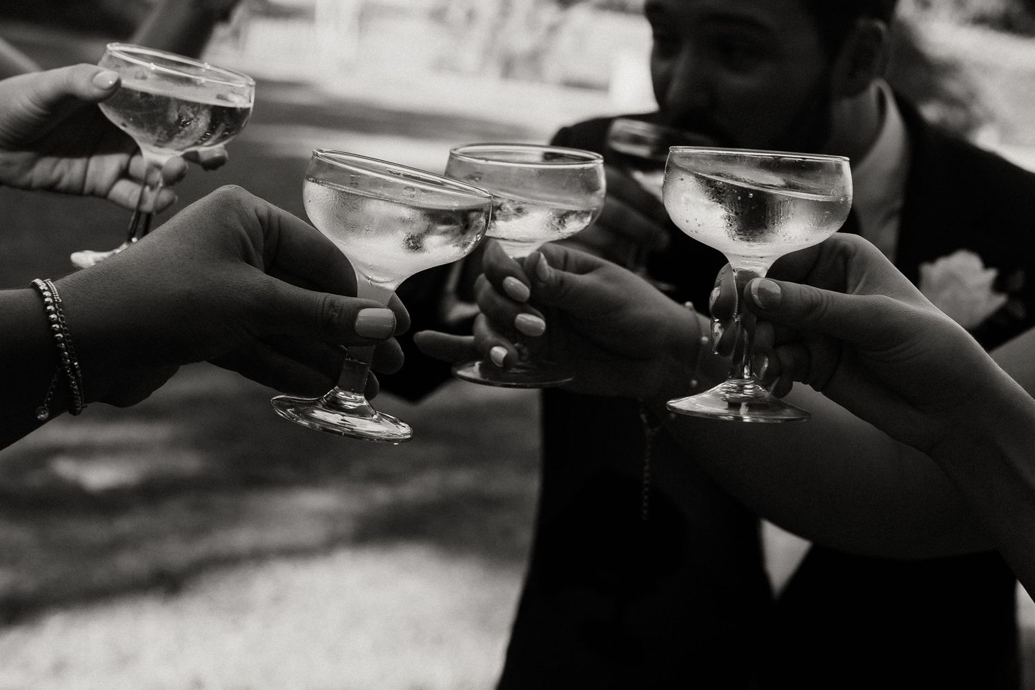 Black and white image of champagne glasses being held during a toast.