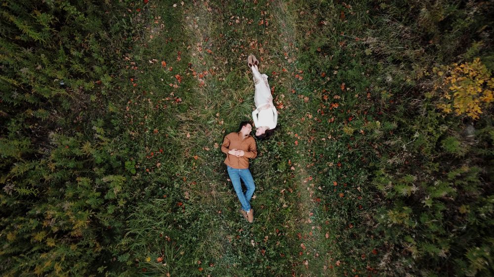 Aerial view of a couple lying on a path through a green forest landscape creating a romantic scene.