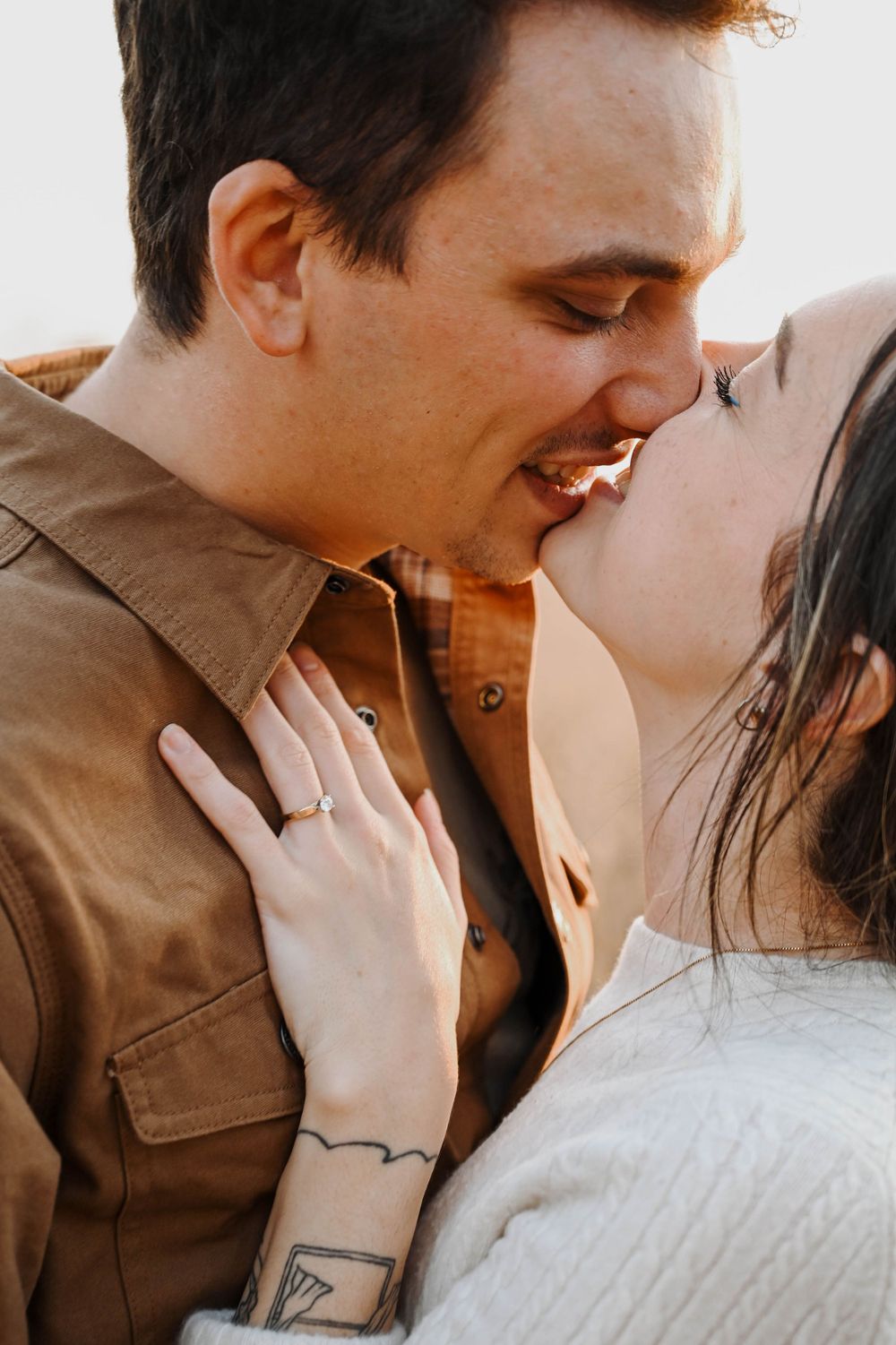 A romantic couple sharing an intimate close-up moment while embracing in natural outdoor lighting.
