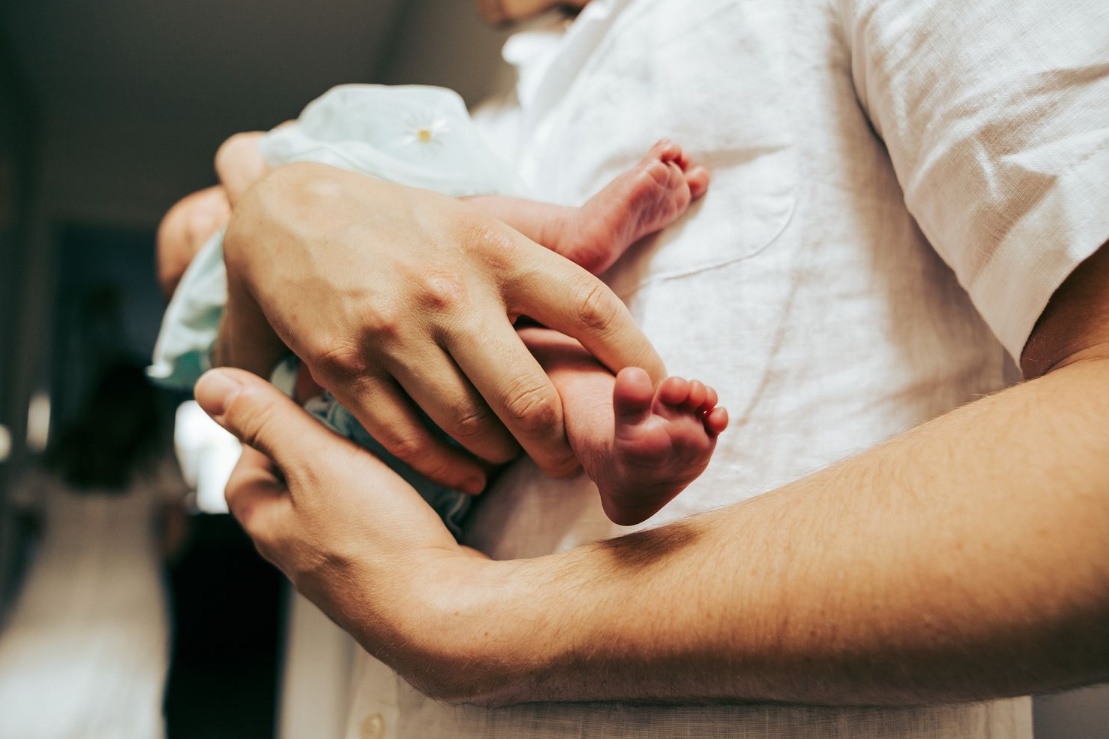 Close-up of hands holding a newborn baby.