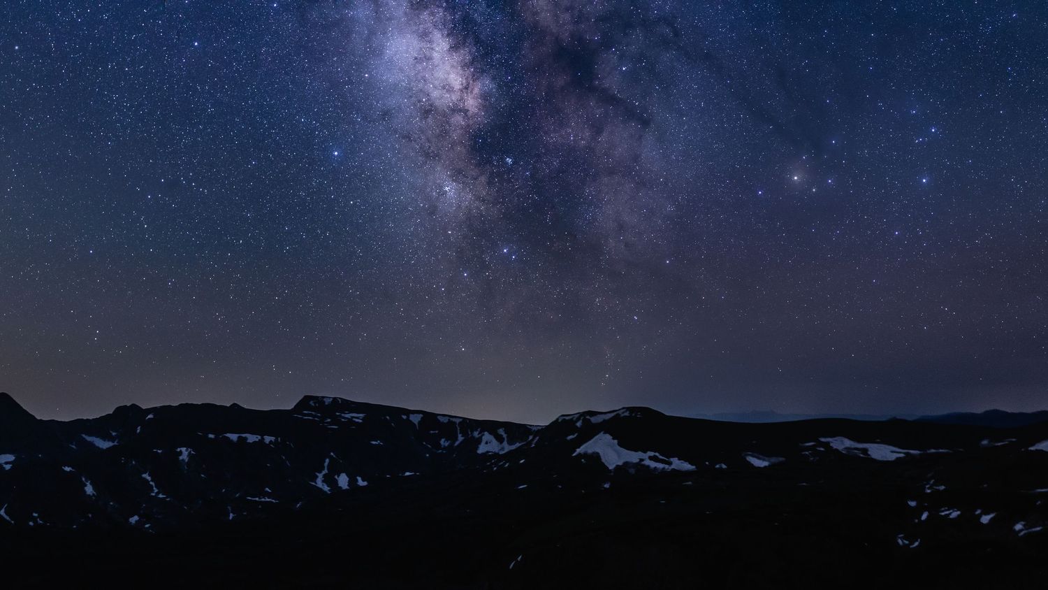 Stunning Milky Way galaxy stretches across dark mountain landscape at night at Rocky Mountain National Park