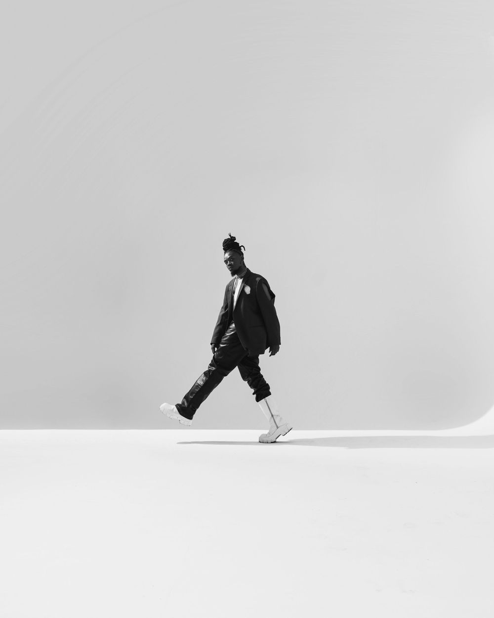 Minimalist black and white photo of person walking against white background.