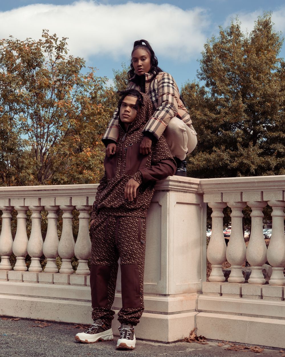 Fashion photograph of two people posing on stone balustrade during autumn.