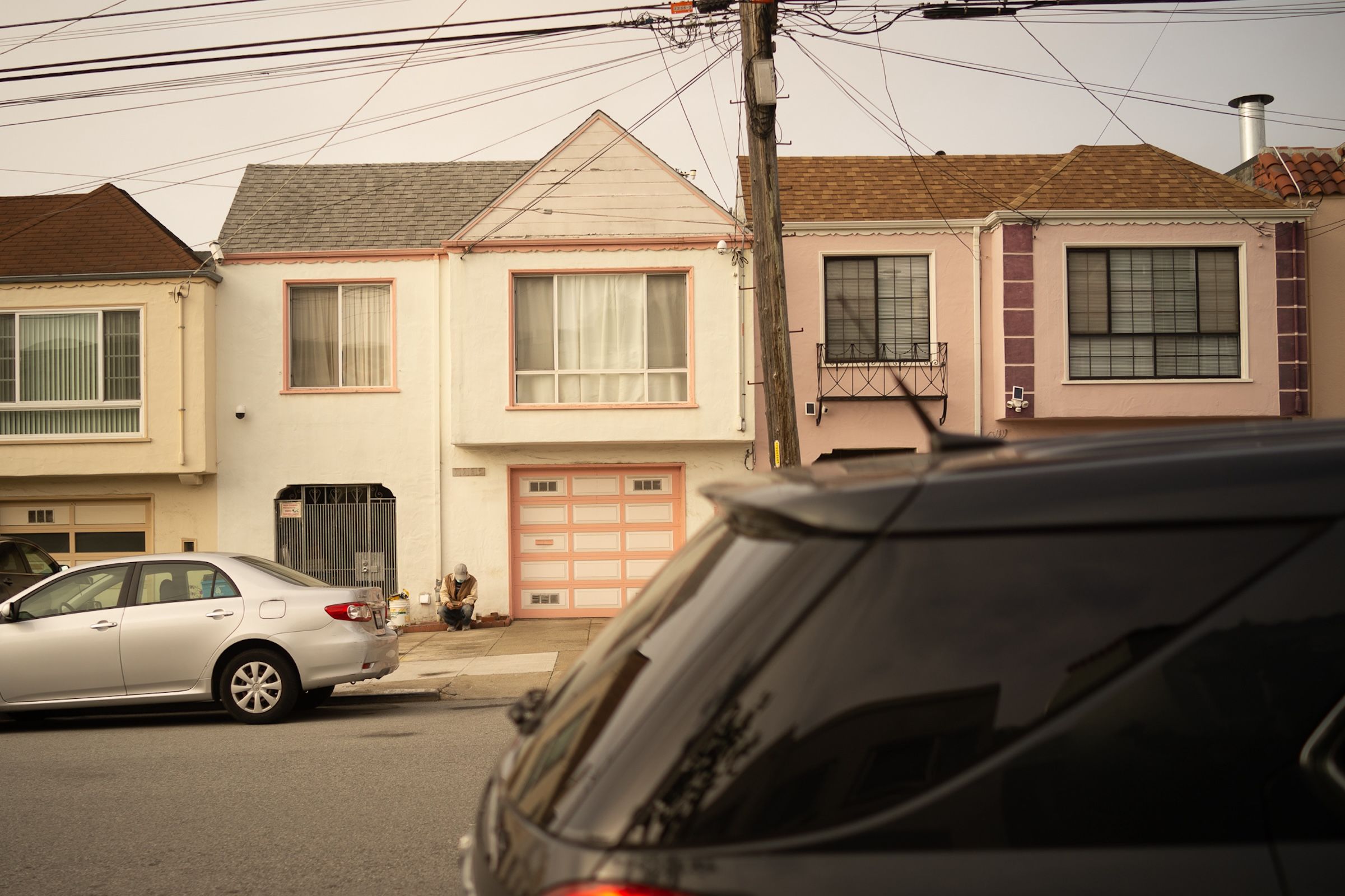 Row of pastel-colored residential homes with garages along a street in San Francisco.