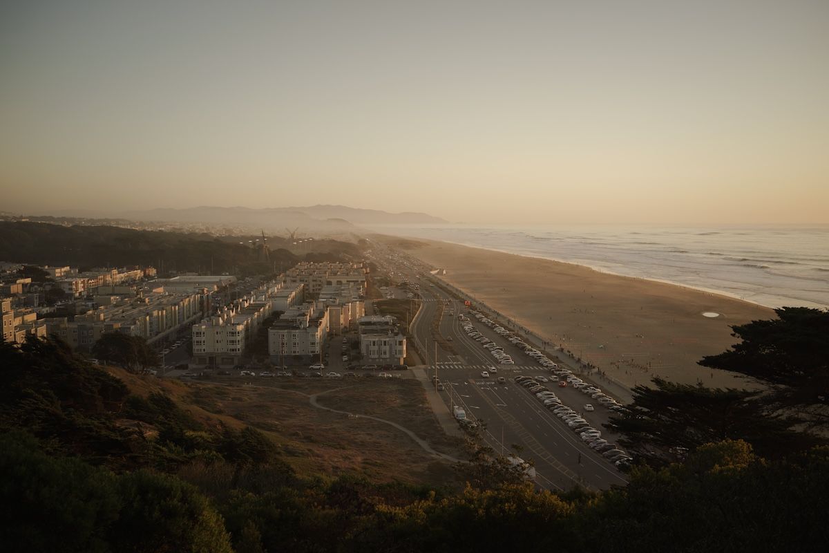 Aerial view of Ocean Beach in San Francisco at sunset showing apartments and coastline.