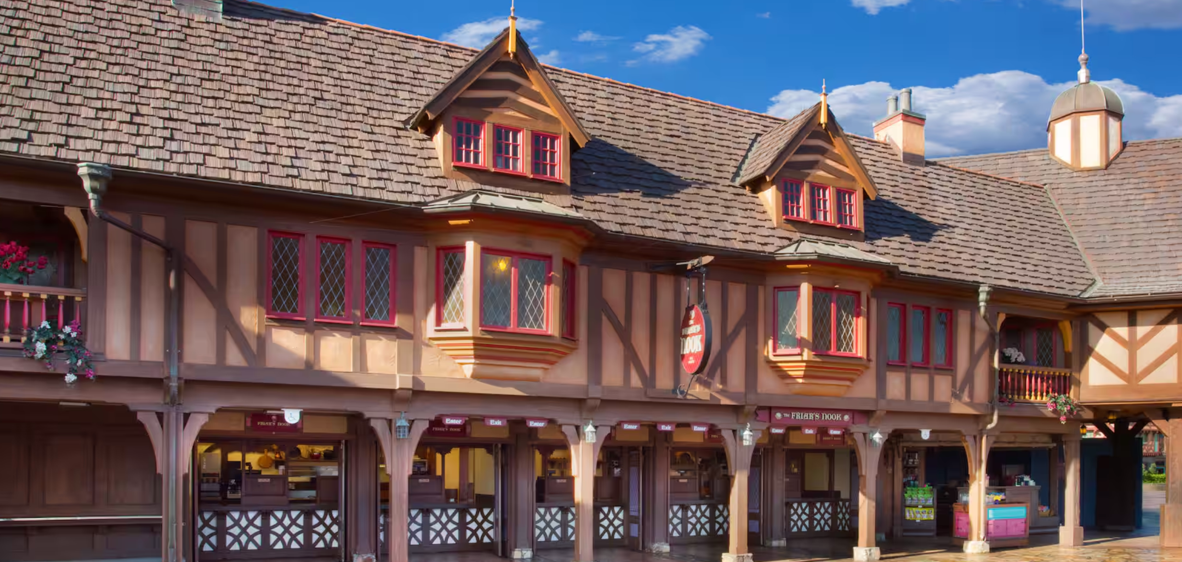A Tudor-style building with red and tan timber framing, dormers, and decorative trim at Walt Disney World's Magic Kingdom.