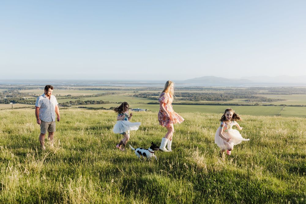 Family enjoying a sunset walk through tall grass in an open field.