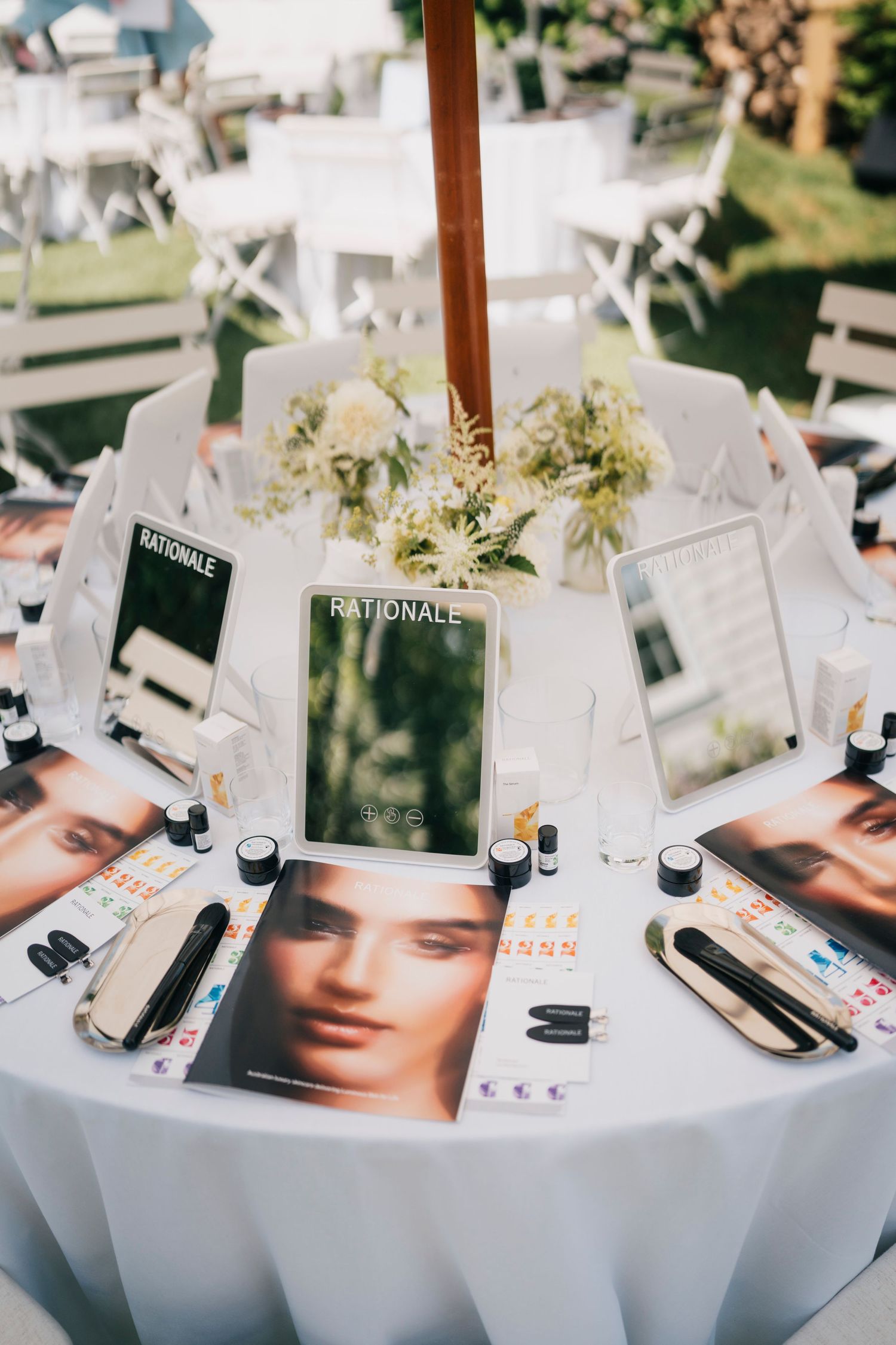 Elegant table settings with white tablecloths, floral centerpieces, and fashion magazines displayed at an upscale event.