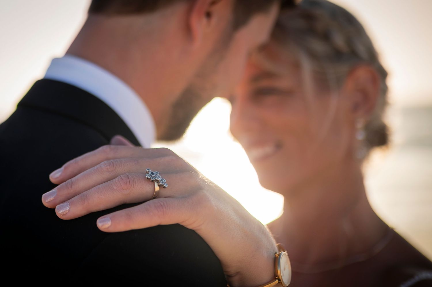 Two people share a tender moment with hands held close to their faces at sunset during a special event.