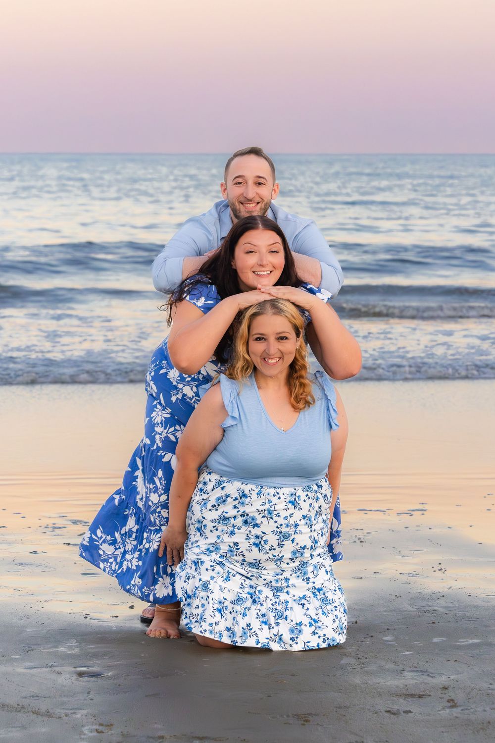 Couple enjoying a sunset photoshoot at the beach wearing coordinated blue and white outfits.