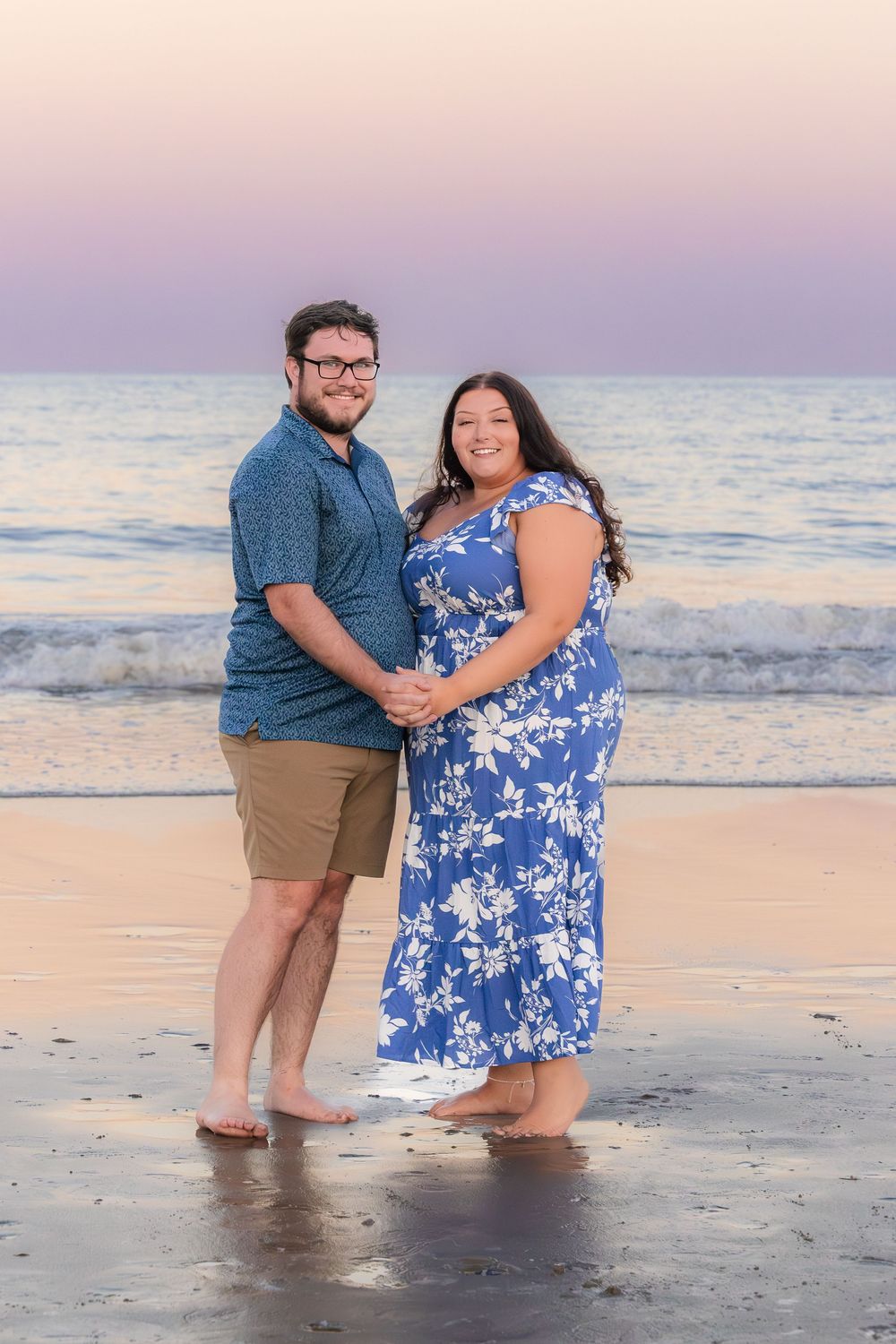 Family enjoying a romantic sunset beach photoshoot with waves crashing in the background.