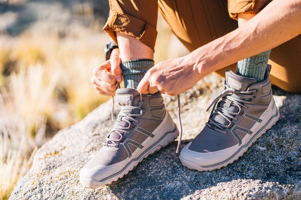 Multiple images showing someone wearing gray sneakers bending down to tie their shoelaces on a rocky surface.
