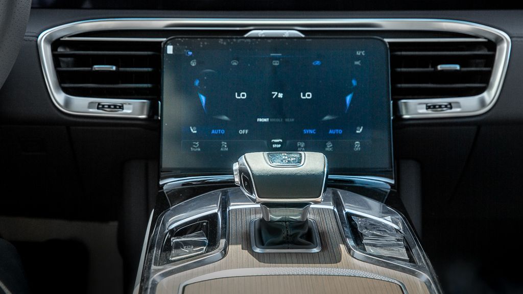 Close-up of luxury vehicle center console with large touchscreen display and gear selector.