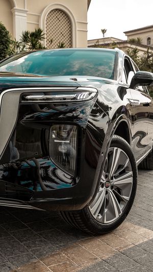 Low angle view of a black luxury car's side profile showing premium wheels and trim.