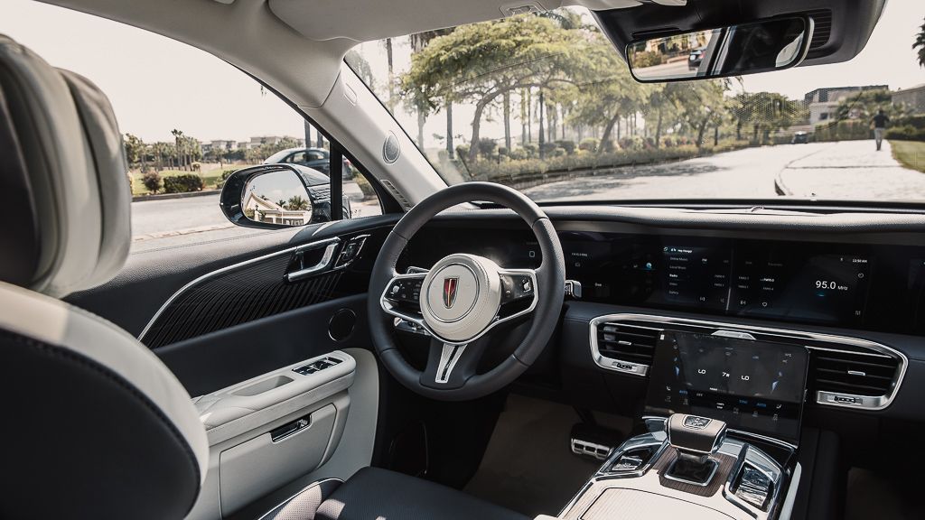 Modern luxury car interior showing steering wheel and dashboard with leather trim.
