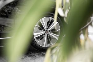 Close-up view of a modern car wheel design through foliage.
