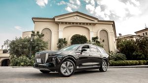 Luxury sedan parked in front of elegant Mediterranean architecture with columns and arches.