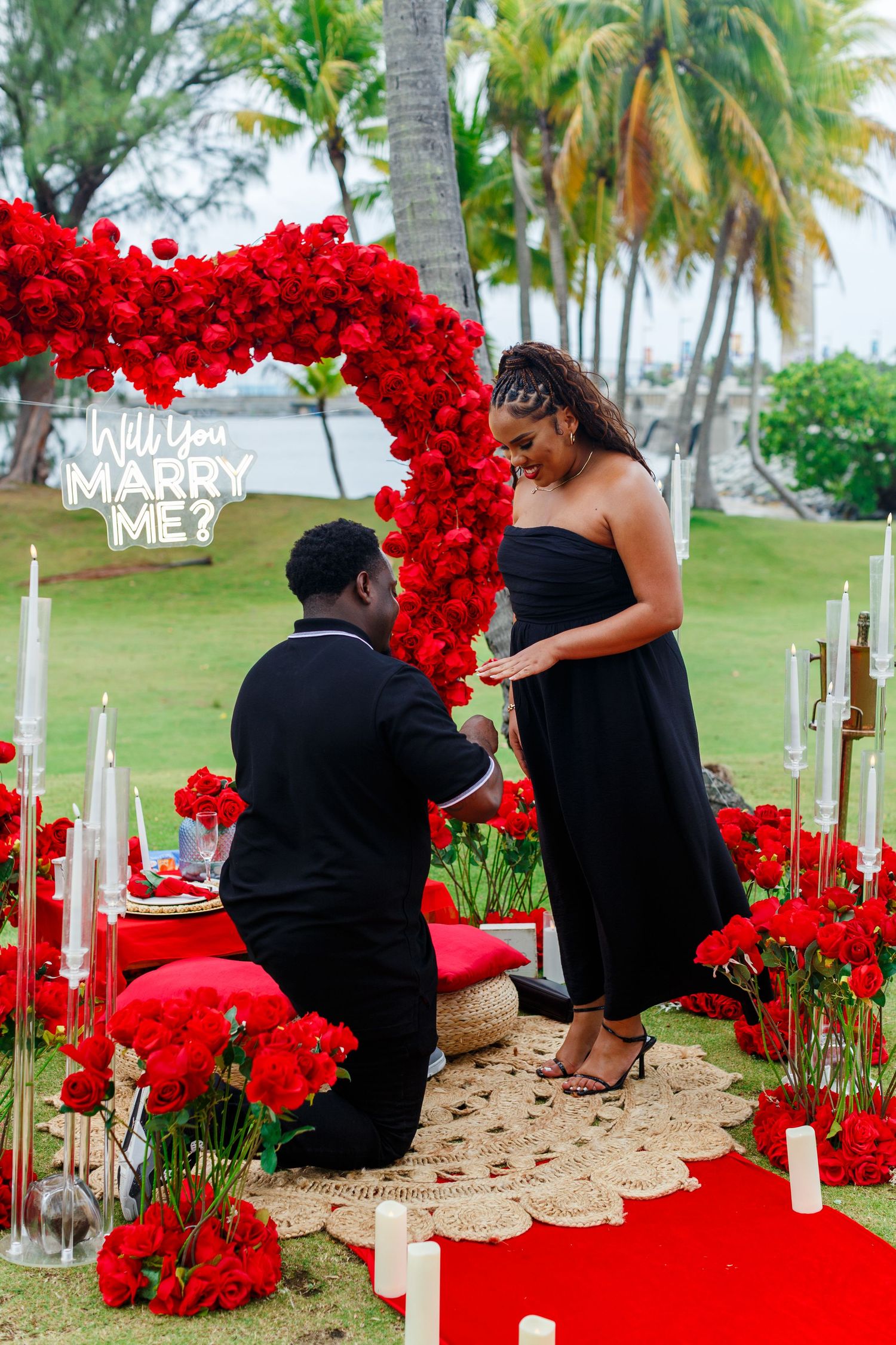 Marriage proposal with couple, red roses, and heart arch near Condado Lagoon in San Juan, Puerto Rico.