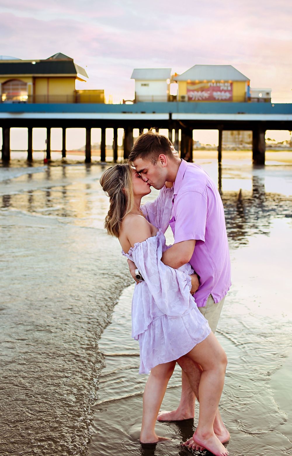 Mom and dad foreheads together posing for maternity beach session while snuggling close