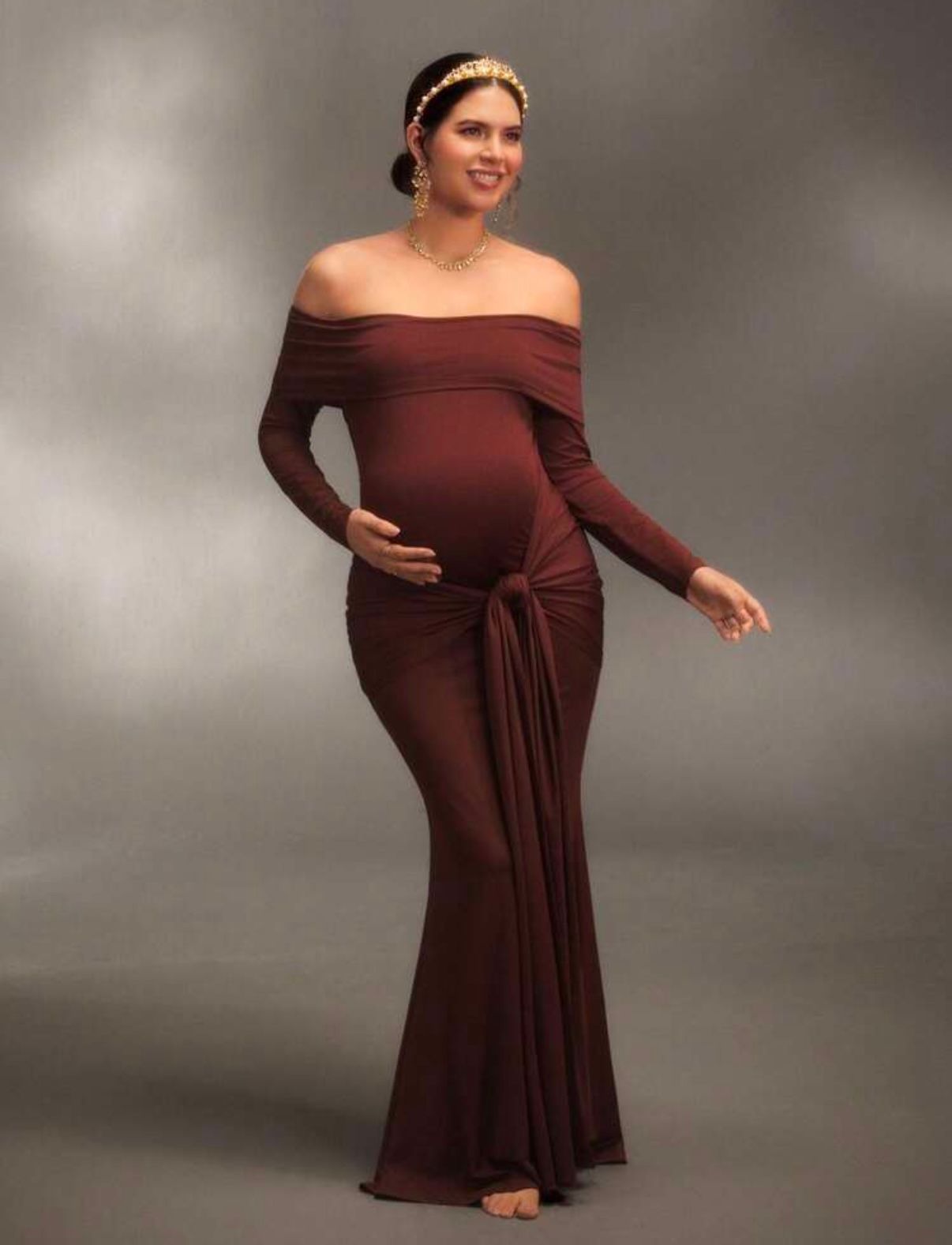 A burgundy off-shoulder dress creates elegant movement in a studio setting.
