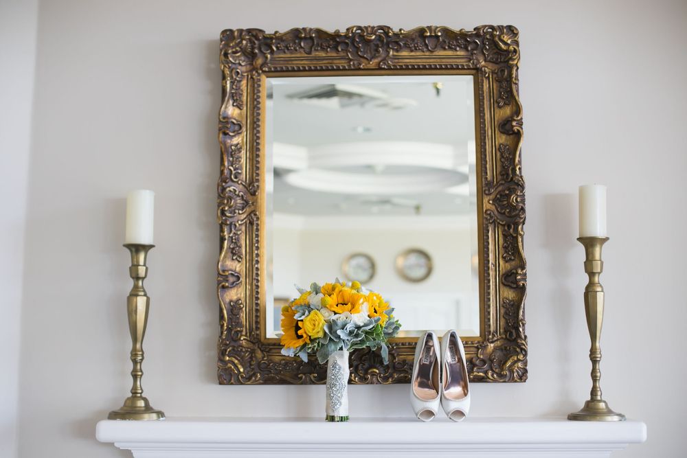 Elegant gold-framed mirror with candle holders on white wall.