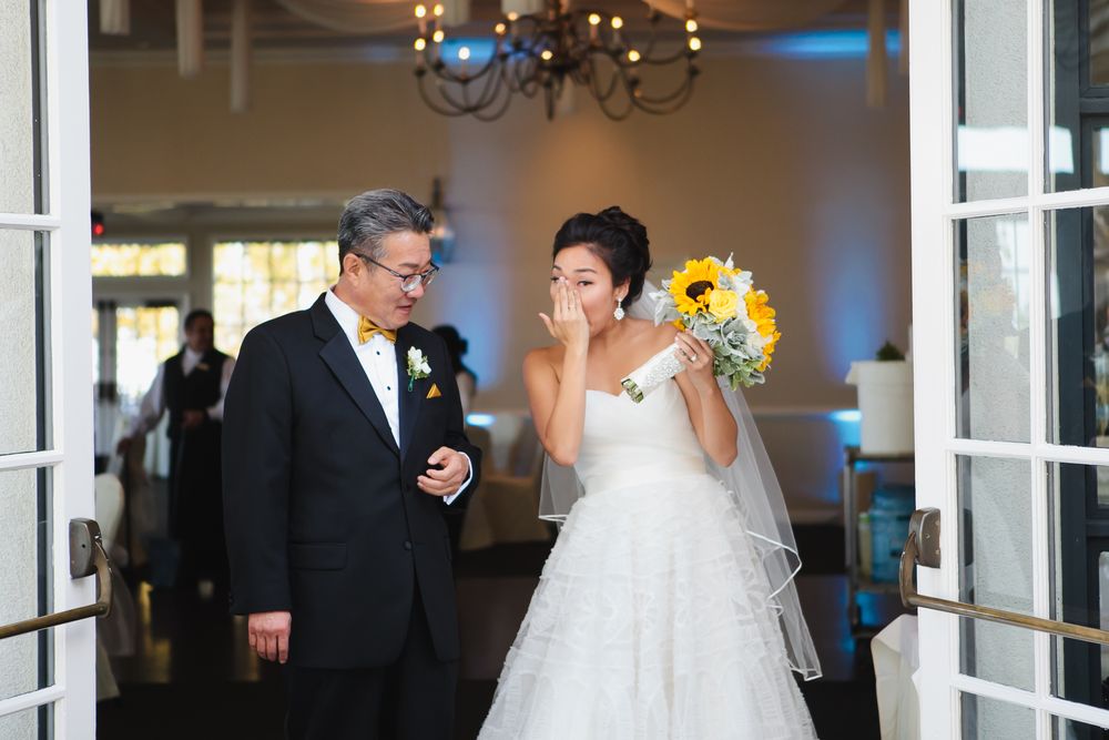 Wedding couple shares joyful moment in elegant indoor venue with chandelier.