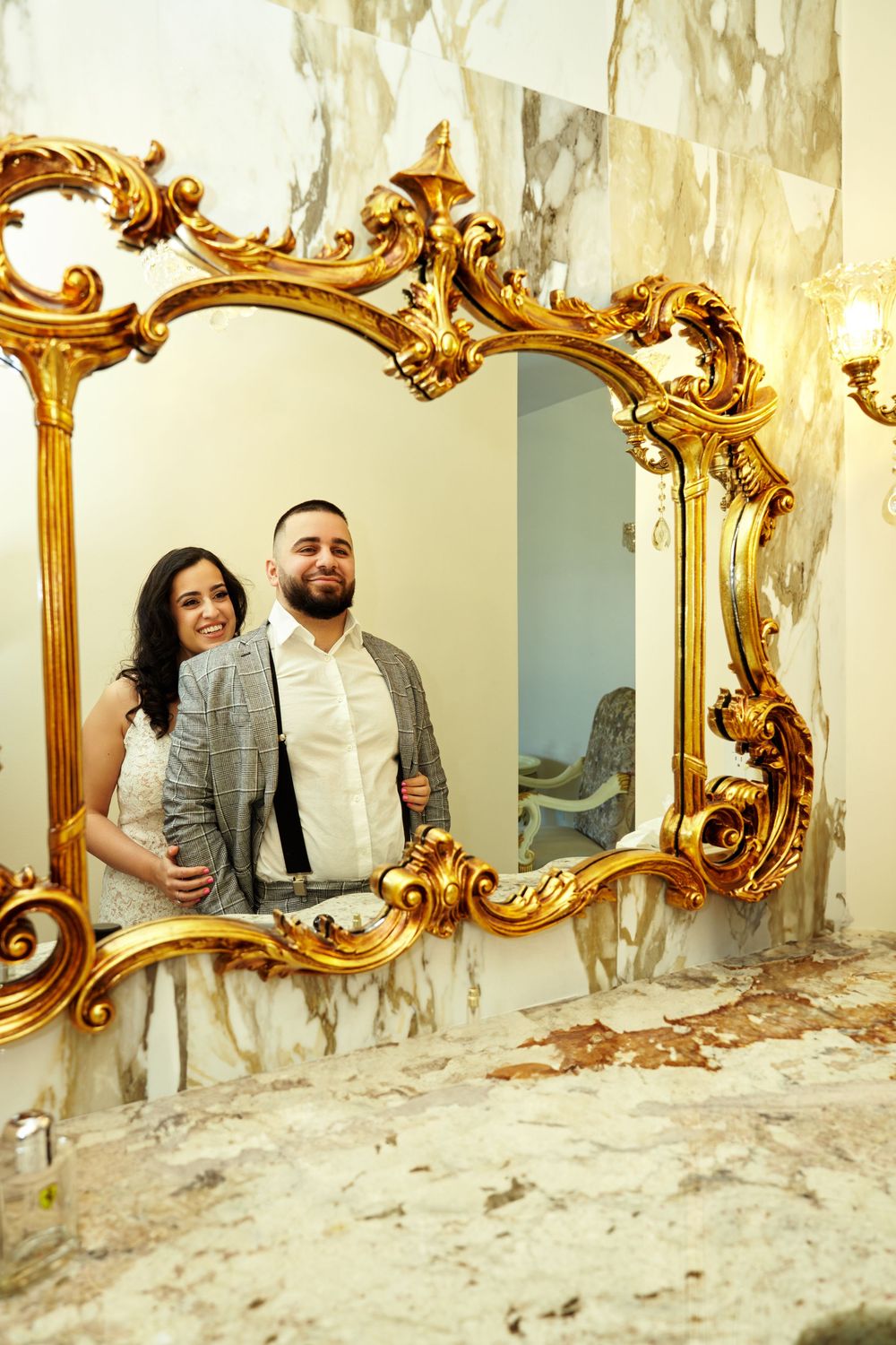 Two people pose together in a series of four shots against a distressed wall with an ornate gold mirror frame. Engagement photoshoot
