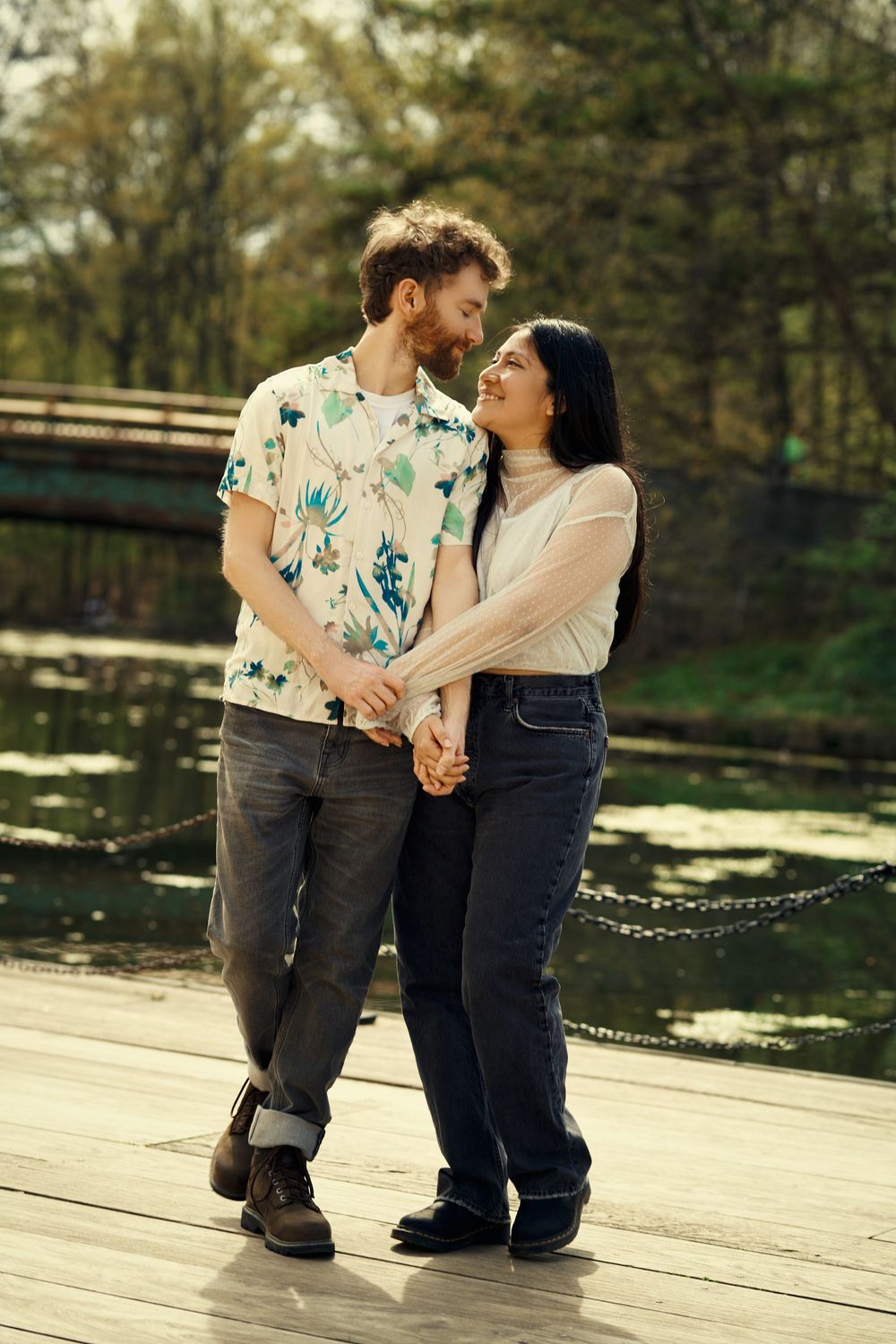 A romantic couple shares intimate moments on a wooden dock by a tranquil lake during golden hour at prospect park boat house