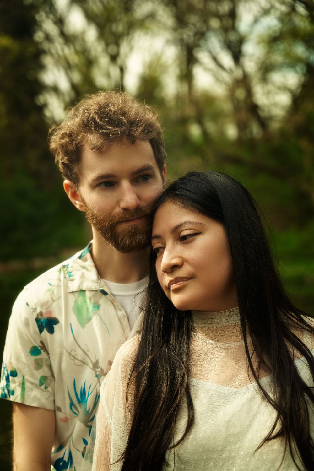 A romantic outdoor portrait of a couple embracing in a forest with soft natural lighting and dreamy bokeh background. engagement shoot